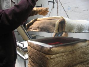 the temporary kiln has a heavy brick lid on a pully.  Inside, gravity pulls the melting glass into the 250lb mold.